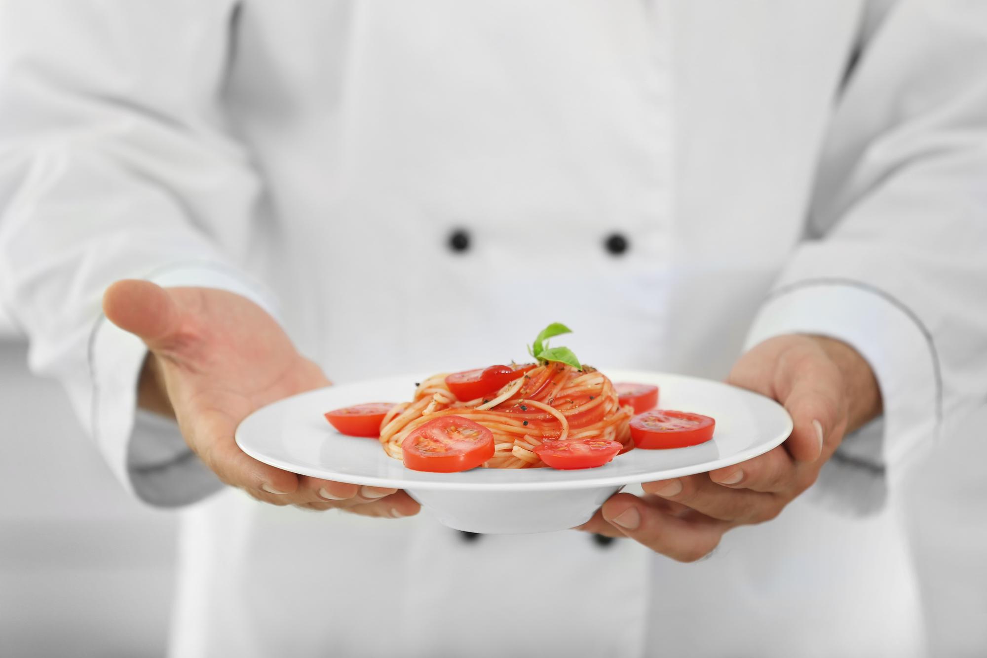 Chef arranging plated dish on wooden table